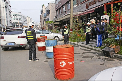 4月22日,市区花源路一家经营户将大油桶摆放门口占道,交警前来查处.