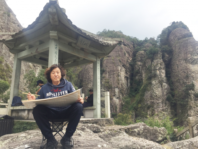 陕西省美术家协会副主席范华先生坐在雁荡山灵峰景区"东瑶台"写生时