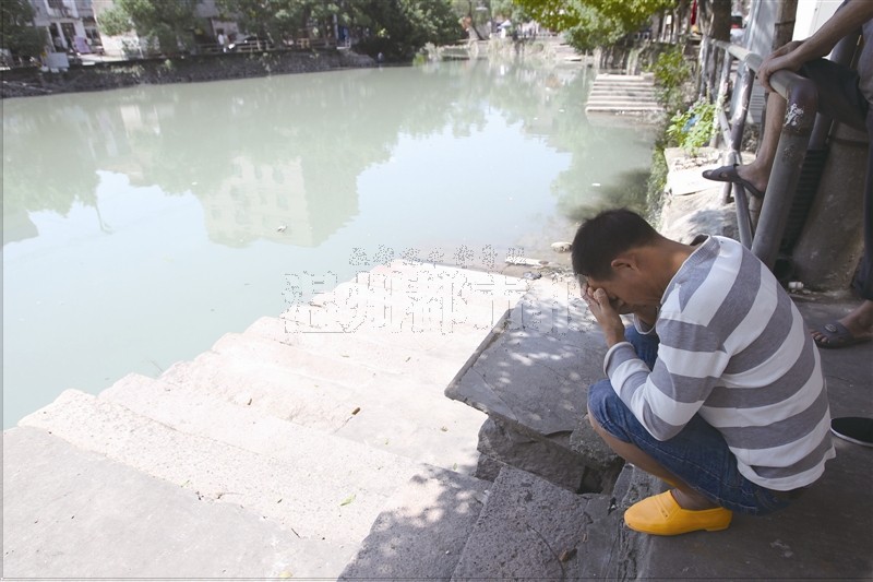 昨天,吴国彪的父亲来到事发地,双手掩面蹲在河边.记者王诚/摄